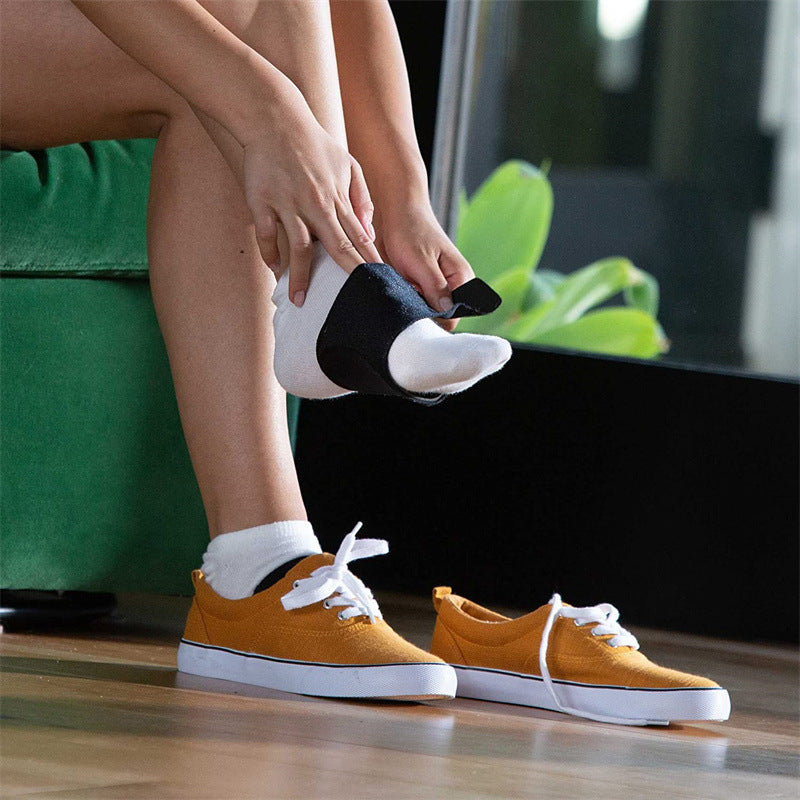 Person putting on a portable foot arch support belt while wearing orange shoes, focusing on foot health.